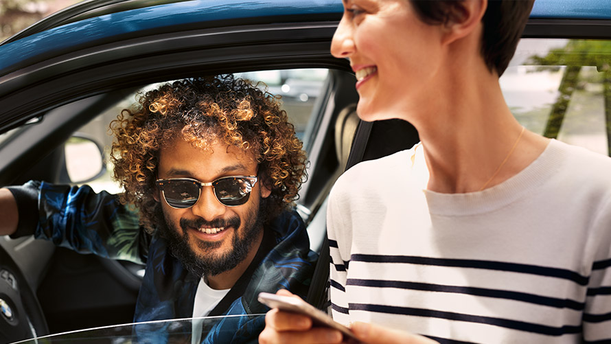 BMW Connected Man and woman sitting on sofa and using BMW Connected on their smartphones