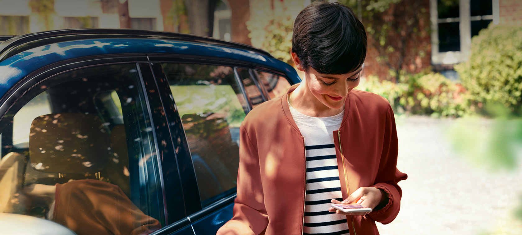 BMWテレサービス スマートフォンを見ている女性 BMWテレサービス BMWの前でスマートフォンを見ている女性