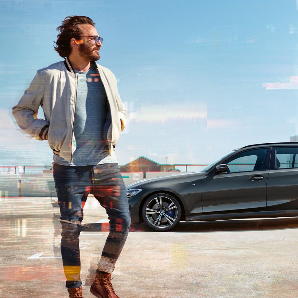 横から写した BMW 3 シリーズ ツーリングのデザイン G21 都市の眺めを背景にした駐車スペースで、横から写したBMW 3 シリーズ ツーリング G21