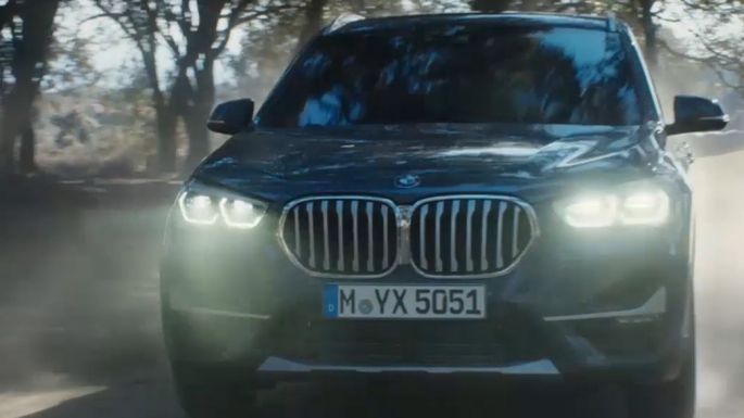 BMW X1、4分の3フロントショット。F48 BMW X1、4分の3フロントショット、自然の風景の前を走行中。F48